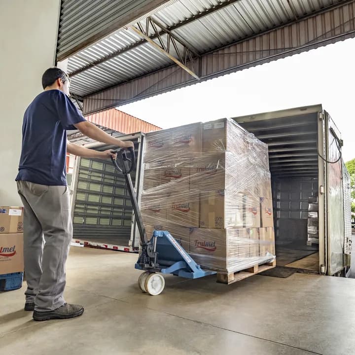 Expedição: funcionário carrega paletes de caixas Frutmel em um caminhão