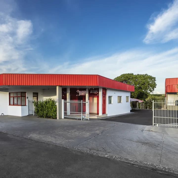 Fachada da Frutmel, com beiral vermelho e o portão de entrada aberto