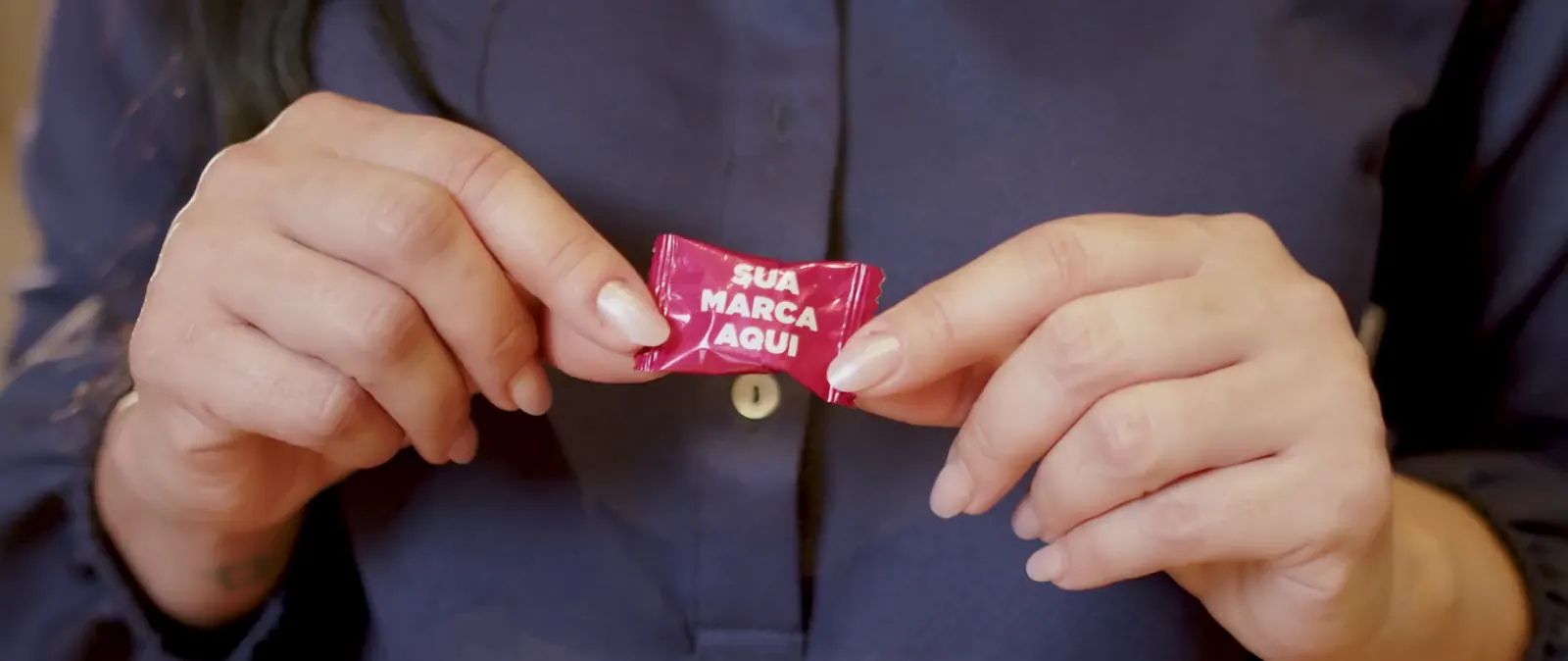 Mãos oferecendo balas com embalagens personalizadas de várias marcas