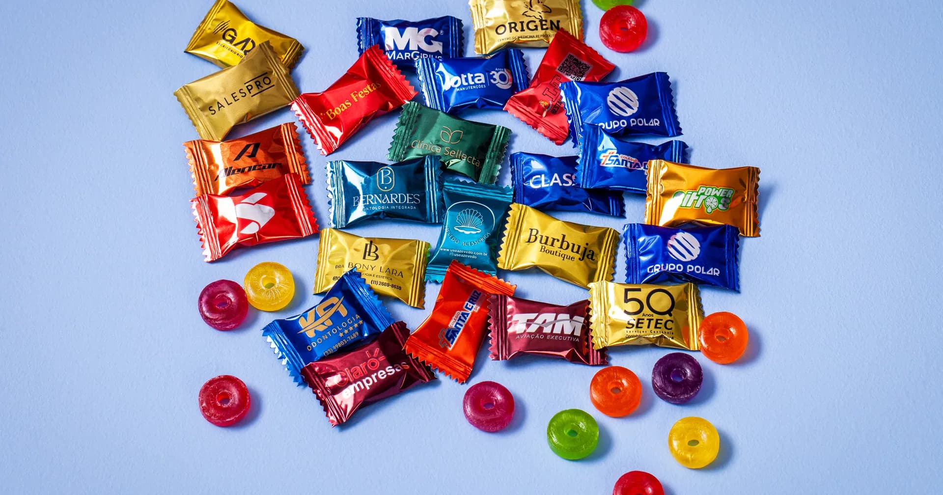 Balas personalizadas de várias marcas, em embalagens coloridas, sobre fundo claro
