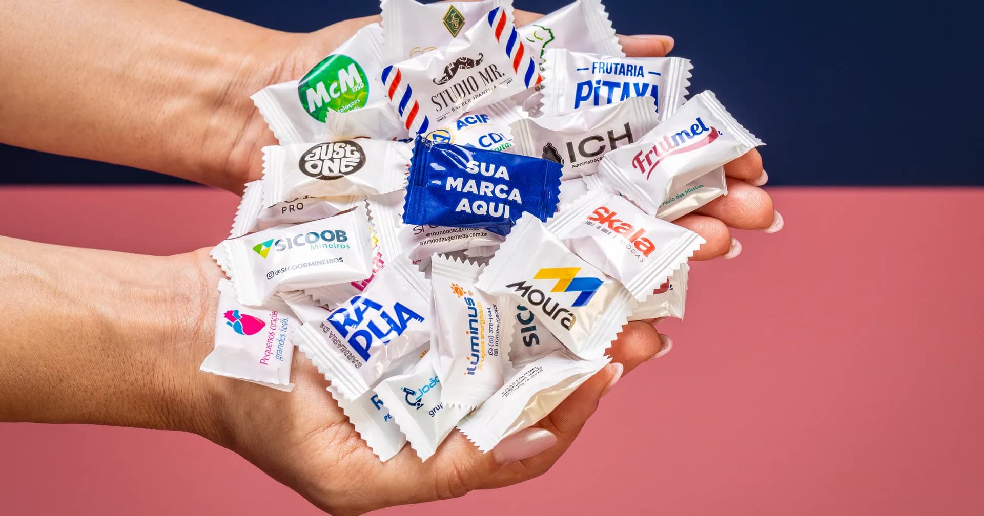 Duas mãos em concha cheias de balas personalizadas com a marca de clínicas e comércios
