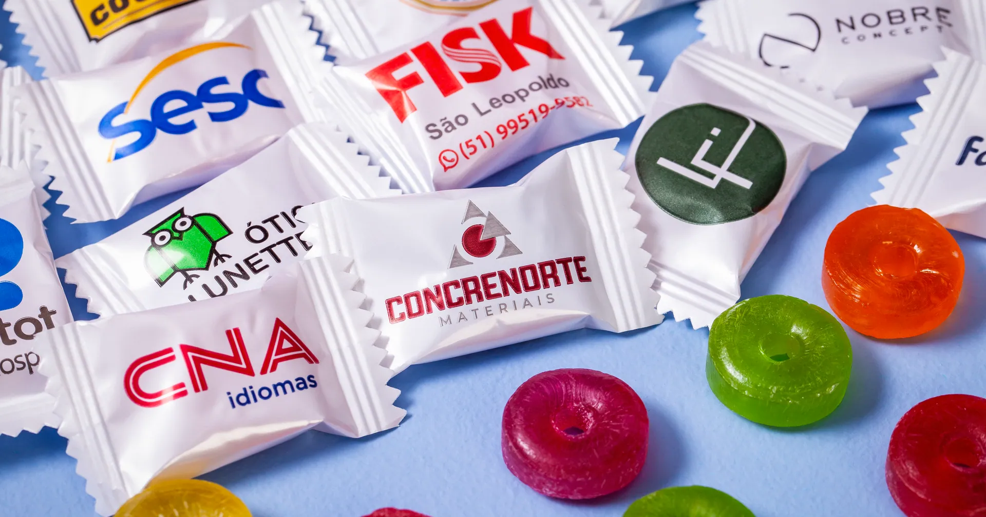 Balas personalizadas com a marca de várias empresas espalhadas sobre fundo azul