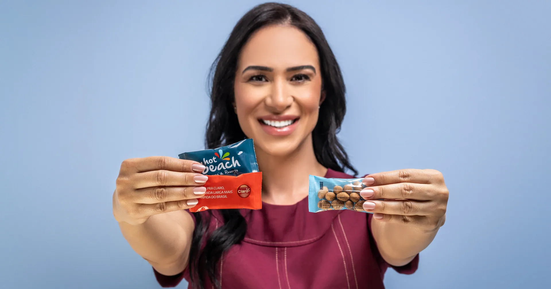 Mulher sorrindo apresenta duas embalagens de brinde comestível personalizado