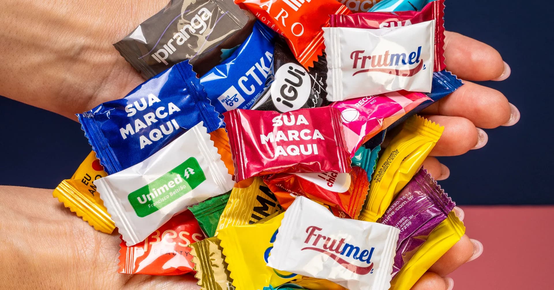 Mão segura um punhado de balas personalizadas com a marca da loja na embalagem